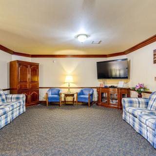 A cozy living room with plaid couches, armchairs, a large TV, and wooden furniture.
