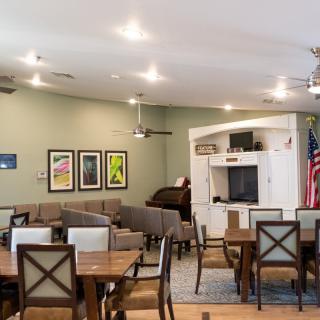 A well-lit dining area with tables and chairs, decorated with wall art and a television.
