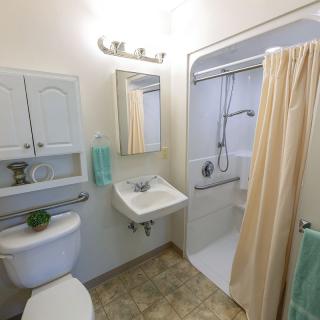 A compact bathroom with a sink, shower, and toilet.