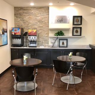 A modern cafe seating area with tables, chairs, and a beverage station.