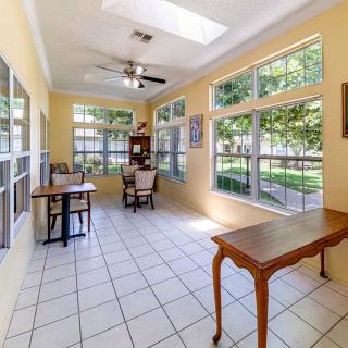 A bright sunroom with large windows, tiled flooring, and cozy furniture.