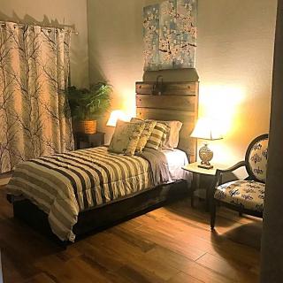 A cozy bedroom featuring a single bed with striped bedding, illuminated by warm lamp lighting.