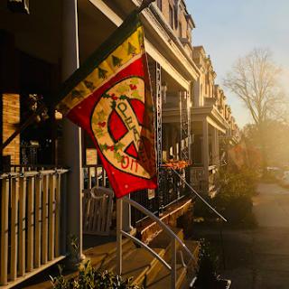 A charming street scene at sunset, featuring a colorful flag and historic buildings.