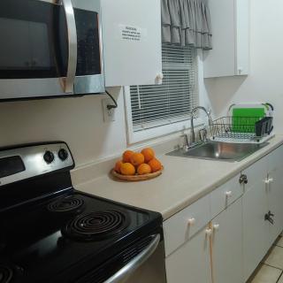A clean and modern kitchen with a microwave, electric stove, and a bowl of oranges on the countertop.