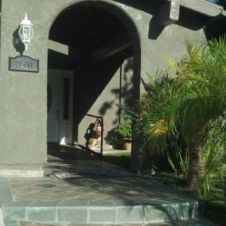 A house entrance with an archway and plants under sunlight.