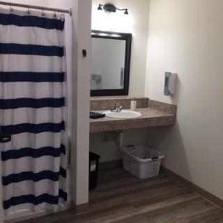 A clean, minimalist bathroom featuring a sink, mirror, and striped shower curtain.