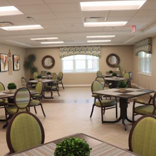 A spacious dining area featuring tables and chairs, decorated with plants and artwork.