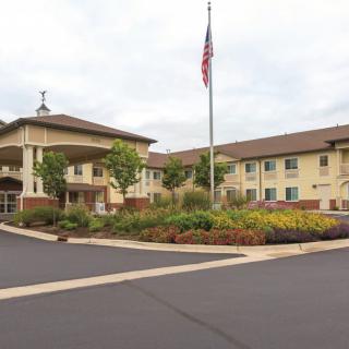 A view of a large building with an American flag, surrounded by landscaped gardens and parking area.