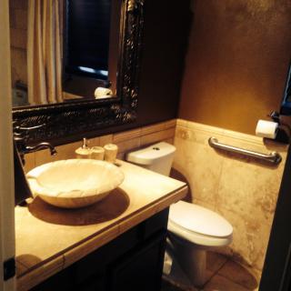 A modern bathroom featuring a vessel sink, large mirror, and toilet in a warm-toned setting.