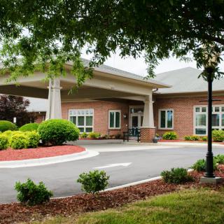 A building entrance surrounded by landscaped greenery and a driveway.