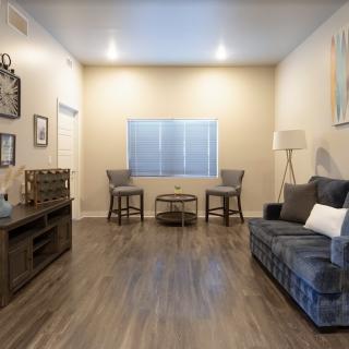 A modern living room with a sofa, chairs, and a wooden floor.