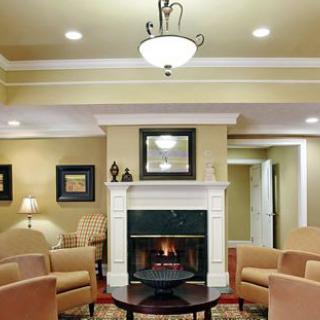 A modern living room featuring a central fireplace, elegant chairs, and a chandelier.