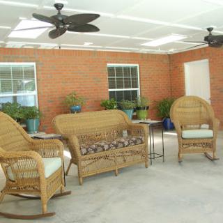 A cozy patio area featuring wicker furniture and ceiling fans, ideal for relaxation.