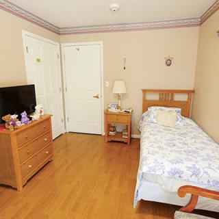 A cozy bedroom with a single bed, wooden furniture, and a television.