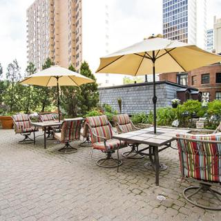 A charming outdoor patio with tables, chairs, and umbrellas set against a city backdrop.