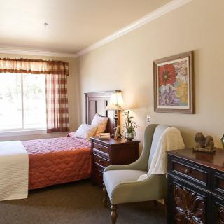 A cozy bedroom with a bed, armchair, and wooden furniture.