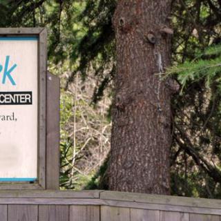 Sign for a park visitor center surrounded by trees.