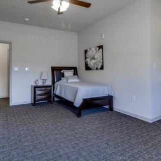 A minimalist bedroom with a single bed, nightstand, and ceiling fan.