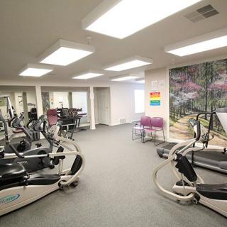 A well-lit gym room featuring exercise equipment such as ellipticals and treadmills.