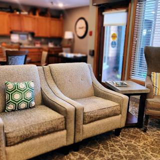 A cozy living room setup featuring stylish chairs and a modern kitchen in the background.