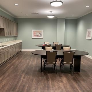 A modern conference room with a long table and chairs, featuring wood flooring and artwork on the walls.
