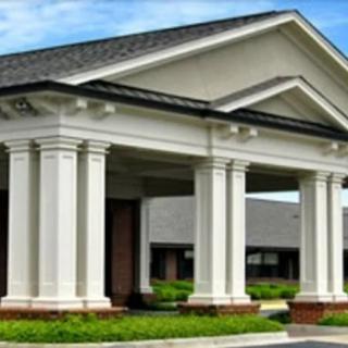 A classic building entrance with white columns and a peaked roof.