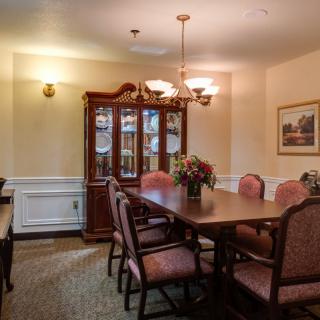 A formal dining room with a wooden table, upholstered chairs, a china cabinet, and elegant lighting.