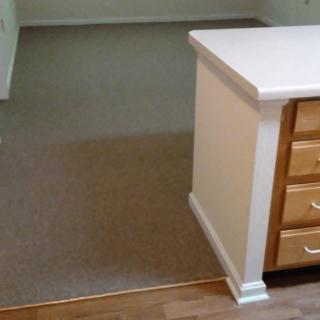A view of a kitchen area with a countertop and drawers next to a carpeted living space.