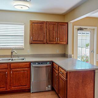 A bright kitchen with wooden cabinets and a modern countertop featuring a sink and dishwasher.