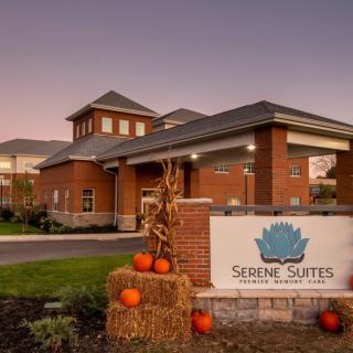 A serene building entrance decorated with pumpkins and autumnal accents during the evening.