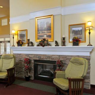 A cozy living room with a fireplace, armchairs, and decorative paintings.