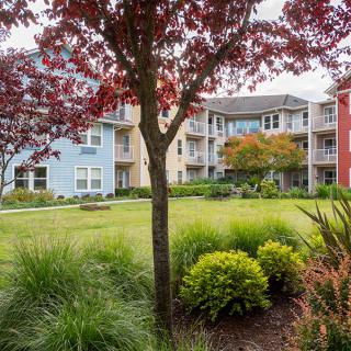 A scenic view of a residential apartment complex with landscaped gardens and vibrant trees.