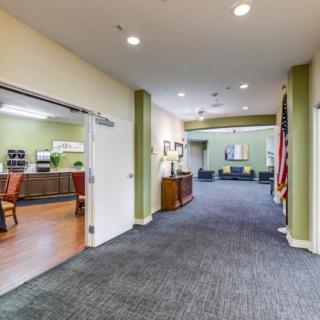 A spacious hallway in an office building with a waiting area and open doors leading to other rooms.