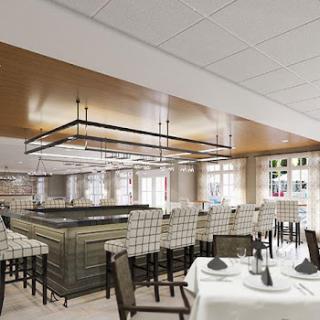 A contemporary restaurant interior featuring a sophisticated bar area and elegantly set dining tables.