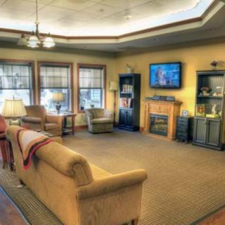 A cozy living room with a sofa, armchairs, and a television mounted above a fireplace.