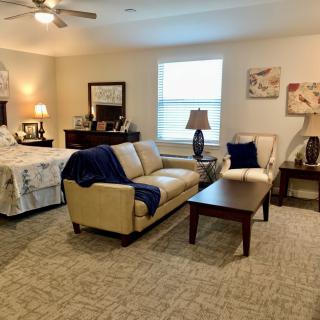 A cozy studio apartment with a combined living and sleeping area, featuring a sofa, bed, and warm lighting.