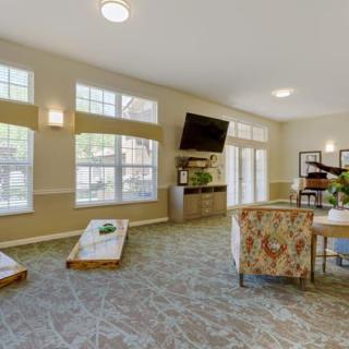 A spacious living room with large windows, modern furniture, and a wall-mounted television.