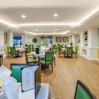 A modern and well-lit dining room with green chairs and neatly arranged tables.