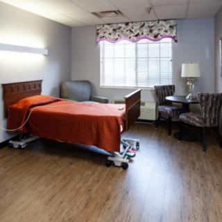 A hospital room with a single patient bed and seating area.