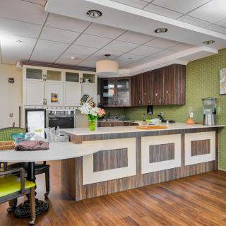A modern kitchen interior featuring a sleek design with wood flooring, green walls, and a spacious countertop.