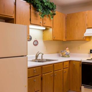 A cozy kitchen with wooden cabinets, a refrigerator, and modern appliances.