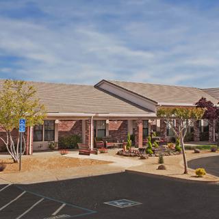 A single-story suburban building with a parking lot and landscaped surroundings on a clear day.