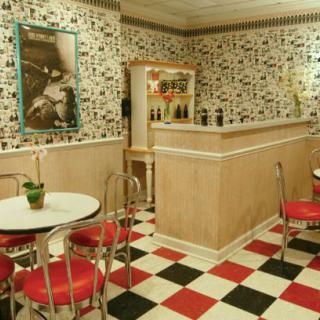 A retro-themed diner with red and white seating, a checkerboard floor, and vintage decor.