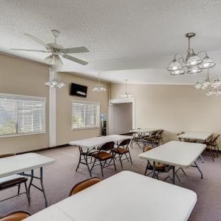 An interior view of a meeting room with tables and chairs, featuring ceiling fans and chandeliers.