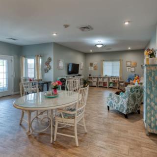 A bright and spacious living room with a dining area, featuring cozy furniture and wood flooring.