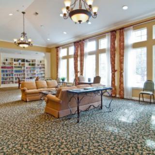 A well-lit living room with comfortable seating and a bookshelf.