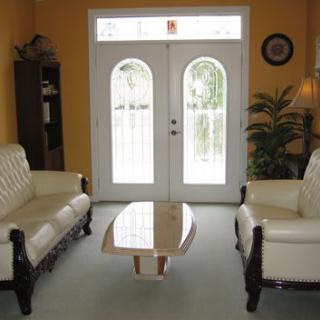 A cozy living room with two sofas, a modern coffee table, and natural light streaming through windowed doors.