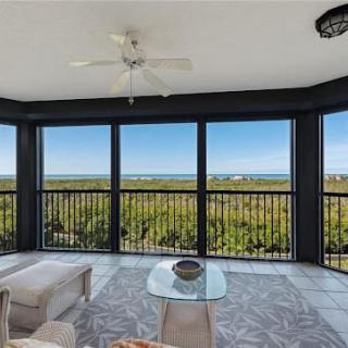 A modern living space with a cozy seating area overlooking an expansive ocean view through large glass windows.