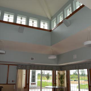 A spacious and well-lit interior featuring high ceilings and large windows.