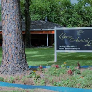 A sign for a business located in a lush outdoor setting, surrounded by greenery and flowers.